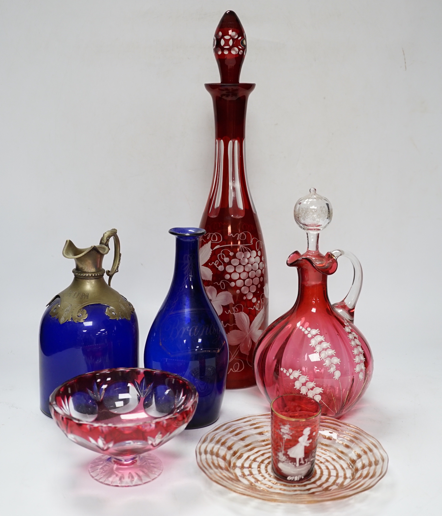 A collection of Bristol blue glassware and other coloured glass including two blue glass decanters, a cranberry, cut glass, decanter, three jugs, pedestal bowls, plates, a pair of miniature vases, etc., tallest 39.5cm (2